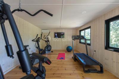 Bâtiment moderne entouré de végétation, avec un chemin pavé et des panneaux indiquant des salles et des logements.