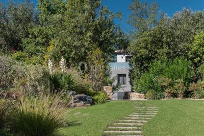 Bâtiment moderne entouré de végétation, avec un chemin pavé et des panneaux indiquant des salles et des logements.