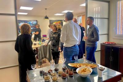 Des personnes assises autour de tables dans une salle lumineuse, partageant un repas ou discutant.