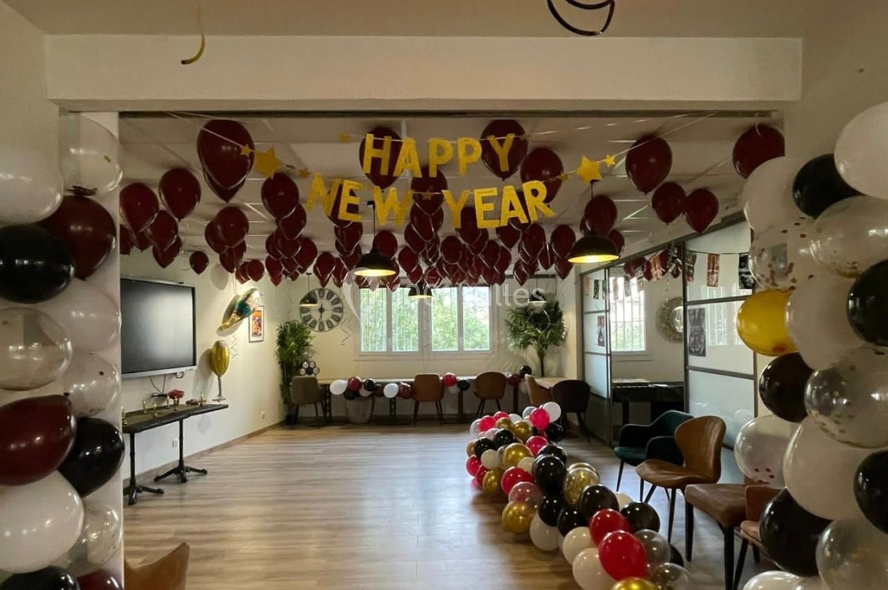 Décoration de salle pour le Nouvel An avec ballons colorés, guirlandes et une bannière ’Happy New Year’.