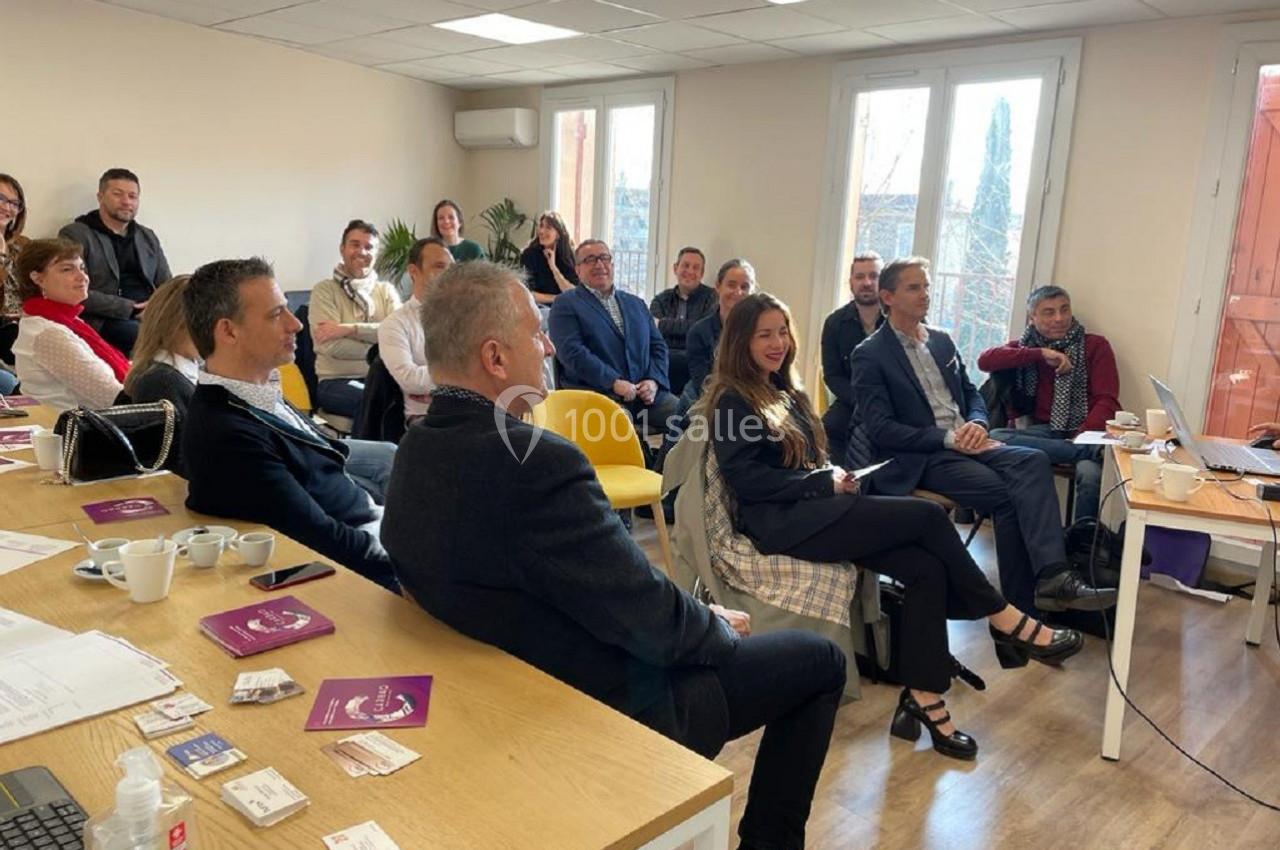 Un groupe de personnes assises dans une salle lumineuse, assistant à une présentation ou réunion.