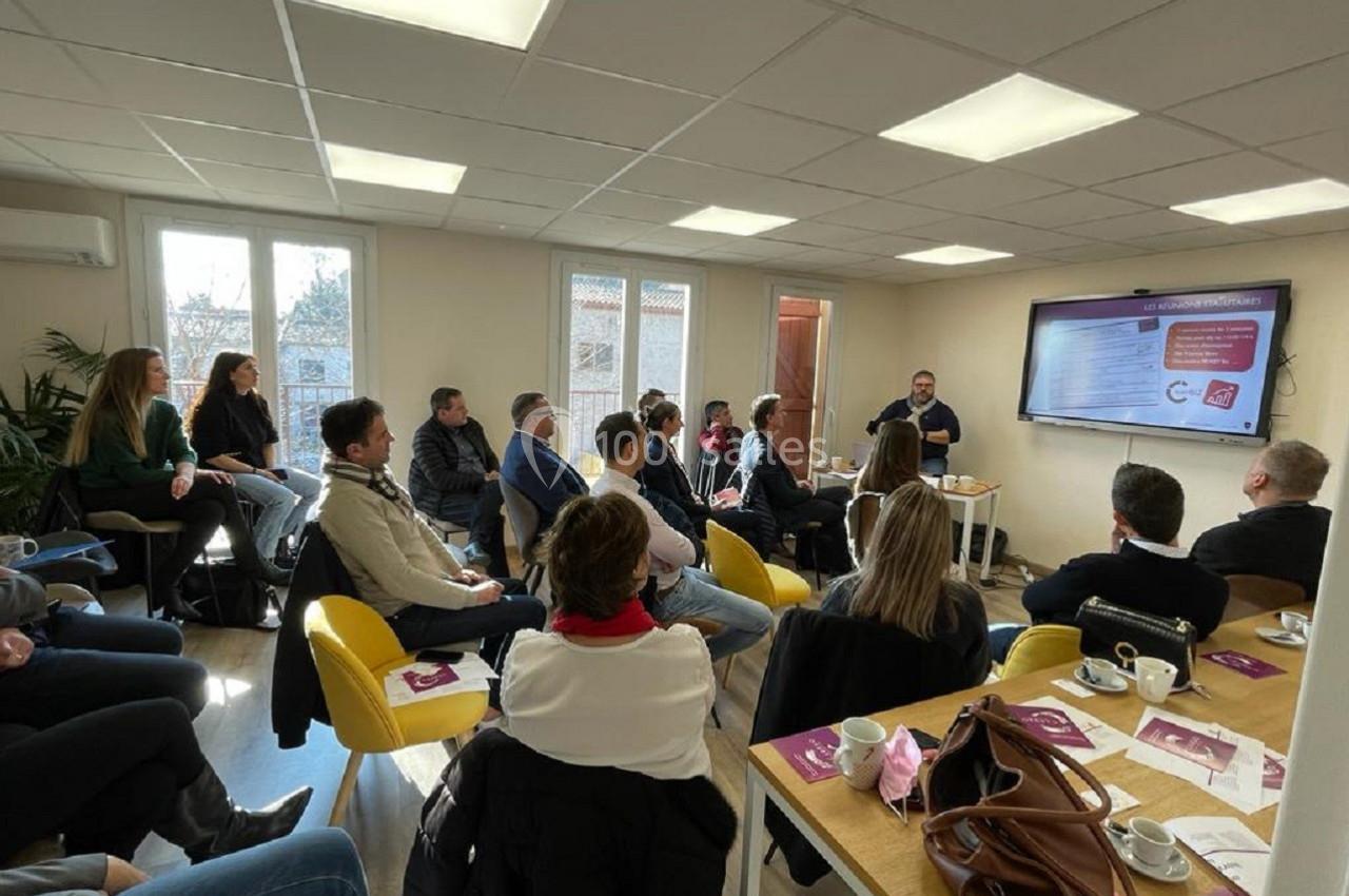 Un groupe de personnes assises dans une salle de réunion, écoutant une présentation affichée sur un écran.
