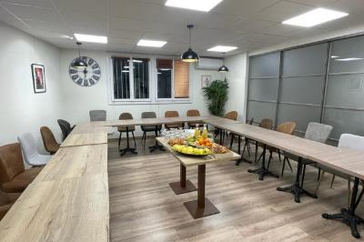 Miniature Location salle La Garde (Var) - City Var #5 Salle de réunion lumineuse avec plusieurs tables, chaises variées, plantes vertes et un écran mural.