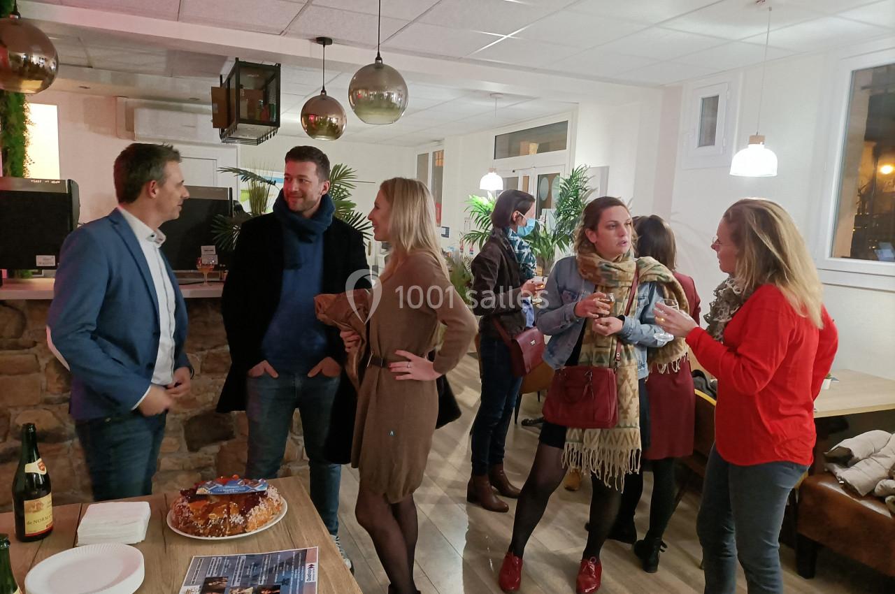 Un groupe de personnes discute dans un espace intérieur convivial avec des tables et des décorations lumineuses.