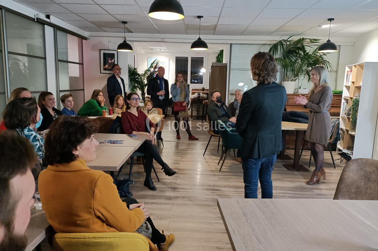 Un groupe de personnes assises et debout dans une salle, écoutant une présentation informelle.