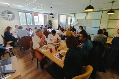 Miniature Location salle La Garde (Var) - City Var #25 Salle de réunion lumineuse avec plusieurs tables, chaises variées, plantes vertes et un écran mural.