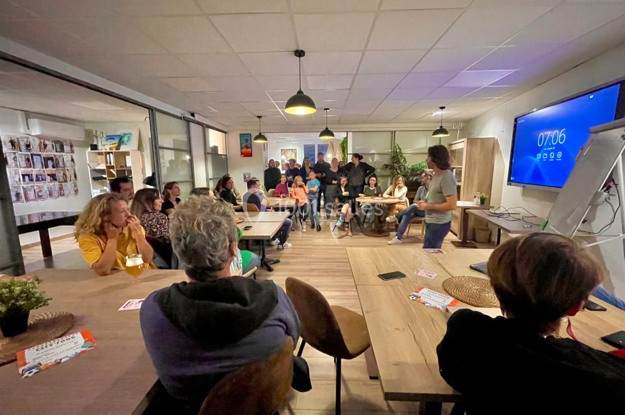Un groupe de personnes assises et debout dans une salle, assistant à une présentation devant un écran.