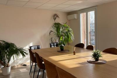 Miniature Location salle La Garde (Var) - City Var #11 Salle de réunion lumineuse avec plusieurs tables, chaises variées, plantes vertes et un écran mural.