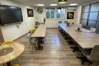 Miniature Location salle La Garde (Var) - City Var #33 Salle de réunion lumineuse avec plusieurs tables, chaises variées, plantes vertes et un écran mural.