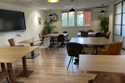 Miniature Location salle La Garde (Var) - City Var #34 Salle de réunion lumineuse avec plusieurs tables, chaises variées, plantes vertes et un écran mural.