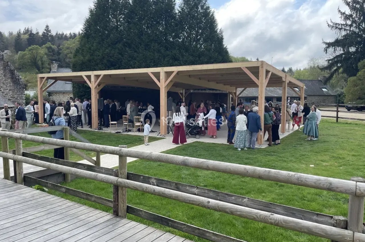 Groupe de personnes rassemblées sous une structure en bois dans un espace extérieur verdoyant.