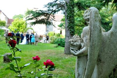 Un couple en tenue de mariage se tient sur un balcon en pierre devant une fenêtre illuminée.
