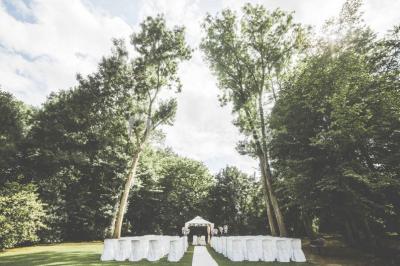 Un couple en tenue de mariage se tient sur un balcon en pierre devant une fenêtre illuminée.