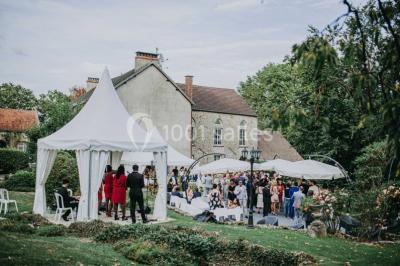 Un couple en tenue de mariage se tient sur un balcon en pierre devant une fenêtre illuminée.