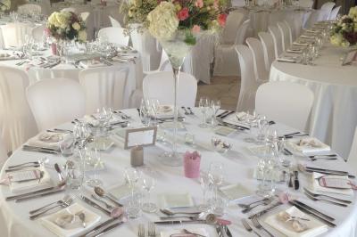 Deux tentes blanches montées sur une pelouse avec des tables et des chaises disposées autour, entourées de verdure.