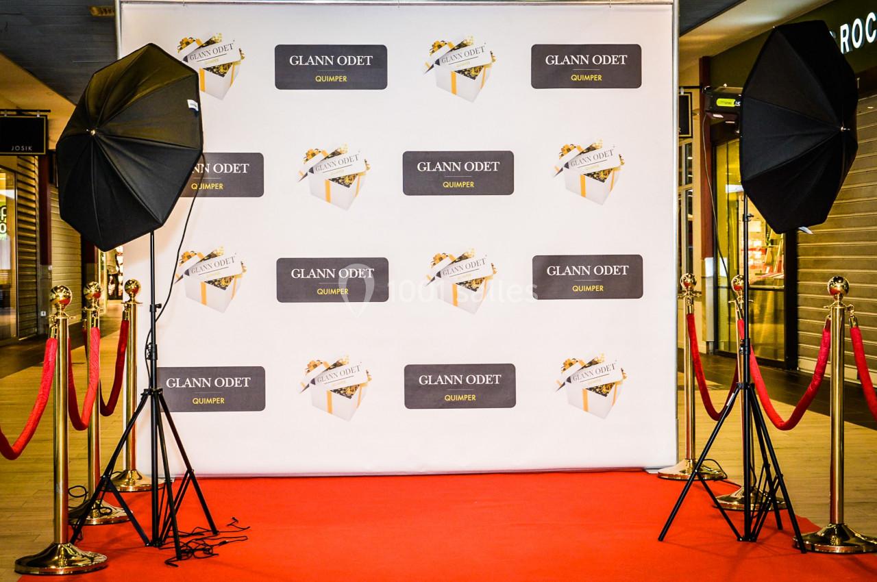 Fond photo avec tapis rouge, cordons rouges, projecteurs et mur décoré de logos ’Glann Odet’.