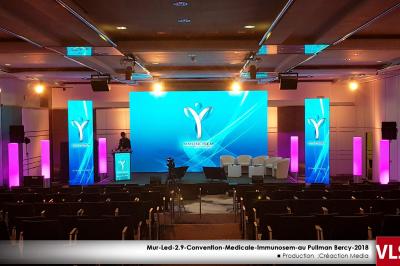 Sapin de Noël décoré de boules dorées et entouré de sacs cadeaux dans un magasin.