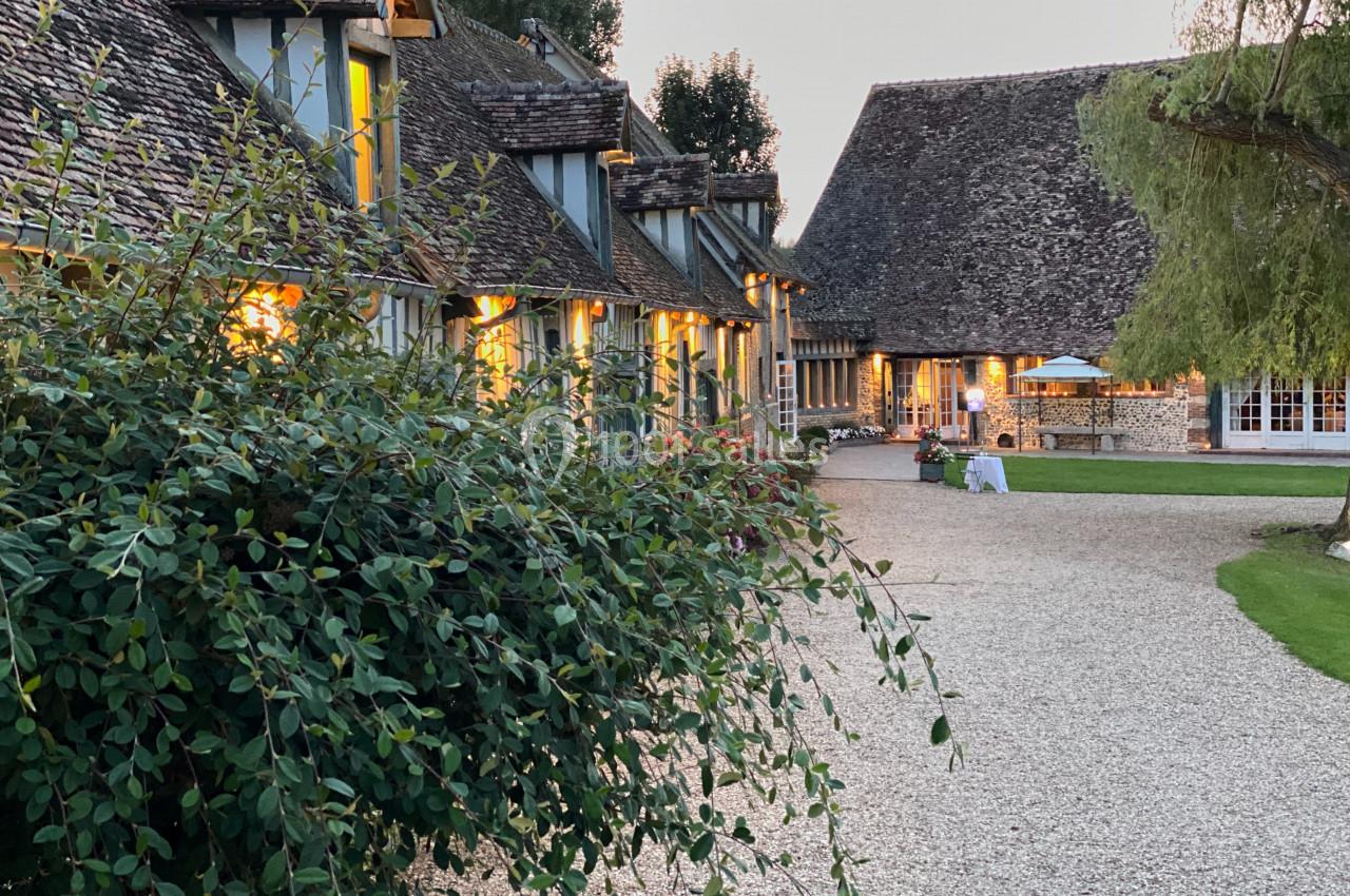 Bâtiments traditionnels en pierre et bois avec toit en tuiles, entourés de verdure et éclairés au crépuscule.
