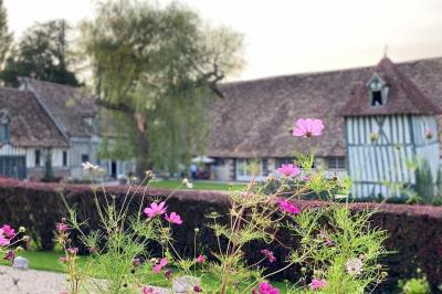 Platines vinyles et disques exposés sur une table en extérieur, avec un jardin verdoyant et un pigeonnier à colombages en…