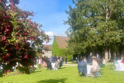 Platines vinyles et disques exposés sur une table en extérieur, avec un jardin verdoyant et un pigeonnier à colombages en…