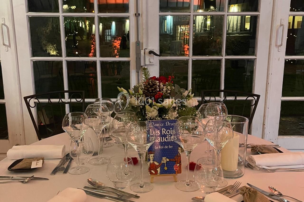 Table dressée pour un dîner, décorée avec des fleurs, des verres et des couverts, sous une guirlande de cœurs numérotés.