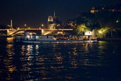 Salle de restaurant sur un bateau avec tables rondes dressées, nappes blanches et vue sur un paysage fluvial.