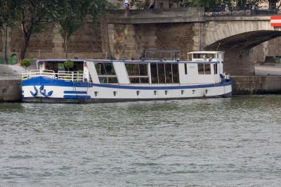 Salle de restaurant sur un bateau avec tables rondes dressées, nappes blanches et vue sur un paysage fluvial.