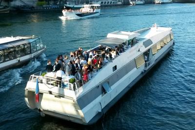 Salle de restaurant sur un bateau avec tables rondes dressées, nappes blanches et vue sur un paysage fluvial.