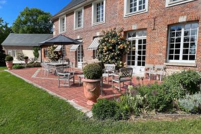Miniature Location salle Corny (Eure) - Le Manoir de Corny #16 Brasero allumé dans une cour gravillonnée devant un bâtiment éclairé avec des murs en bois et des portes vitrées.