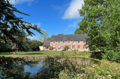 Miniature Location salle Corny (Eure) - Le Manoir de Corny #17 Brasero allumé dans une cour gravillonnée devant un bâtiment éclairé avec des murs en bois et des portes vitrées.