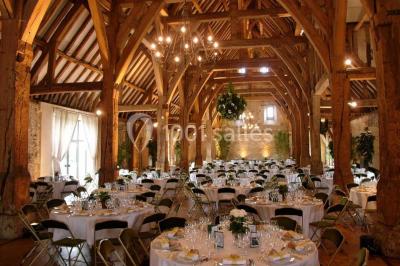 Miniature Location salle Corny (Eure) - Le Manoir de Corny #12 Brasero allumé dans une cour gravillonnée devant un bâtiment éclairé avec des murs en bois et des portes vitrées.
