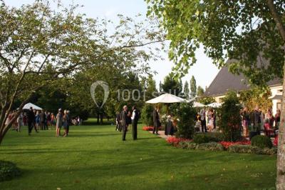 Miniature Location salle Corny (Eure) - Le Manoir de Corny #6 Brasero allumé dans une cour gravillonnée devant un bâtiment éclairé avec des murs en bois et des portes vitrées.
