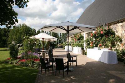 Miniature Location salle Corny (Eure) - Le Manoir de Corny #14 Brasero allumé dans une cour gravillonnée devant un bâtiment éclairé avec des murs en bois et des portes vitrées.