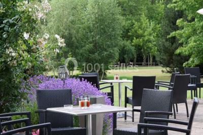 Miniature Location salle Corny (Eure) - Le Manoir de Corny #11 Brasero allumé dans une cour gravillonnée devant un bâtiment éclairé avec des murs en bois et des portes vitrées.