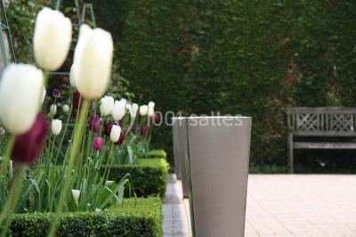 Miniature Location salle Corny (Eure) - Le Manoir de Corny #15 Brasero allumé dans une cour gravillonnée devant un bâtiment éclairé avec des murs en bois et des portes vitrées.