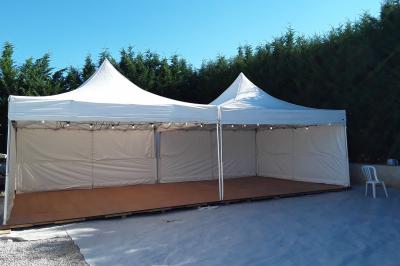 Salle décorée pour un mariage avec des tables rondes recouvertes de nappes blanches et chemins de table rouges.