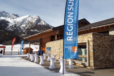 Salle décorée pour un mariage avec des tables rondes recouvertes de nappes blanches et chemins de table rouges.
