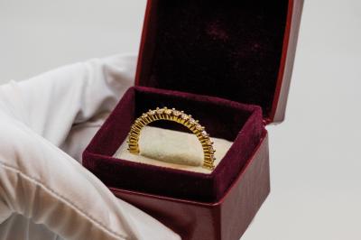 Anneaux en métal de différentes formes, textures et couleurs suspendus en arc sur fond blanc.