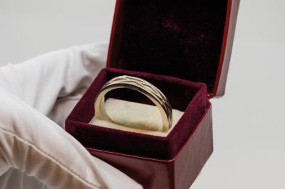 Anneaux en métal de différentes formes, textures et couleurs suspendus en arc sur fond blanc.