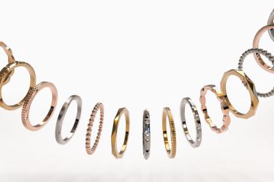 Anneaux en métal de différentes formes, textures et couleurs suspendus en arc sur fond blanc.