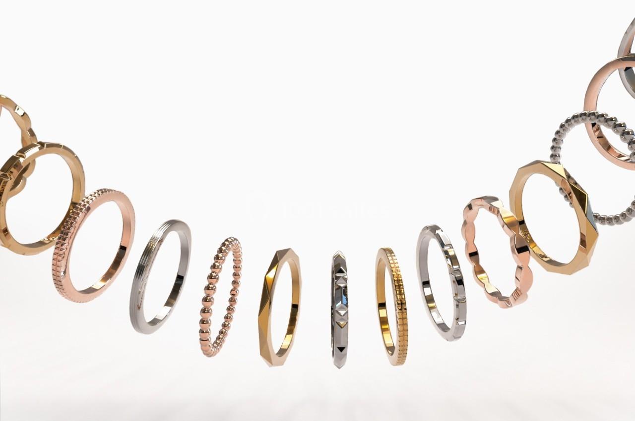 Anneaux en métal de différentes formes, textures et couleurs suspendus en arc sur fond blanc.