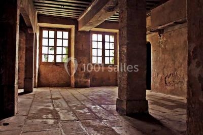 Bâtiment ancien avec façade décrépite, entouré d'une cour herbeuse et d'arbres dénudés en arrière-plan.