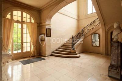 Bâtiment ancien avec façade décrépite, entouré d'une cour herbeuse et d'arbres dénudés en arrière-plan.