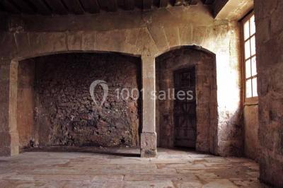 Bâtiment ancien avec façade décrépite, entouré d'une cour herbeuse et d'arbres dénudés en arrière-plan.