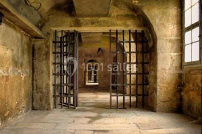 Bâtiment ancien avec façade décrépite, entouré d'une cour herbeuse et d'arbres dénudés en arrière-plan.