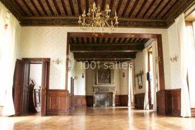 Bâtiment ancien avec façade décrépite, entouré d'une cour herbeuse et d'arbres dénudés en arrière-plan.