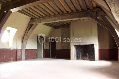 Bâtiment ancien avec façade décrépite, entouré d'une cour herbeuse et d'arbres dénudés en arrière-plan.