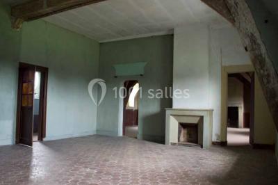 Bâtiment ancien avec façade décrépite, entouré d'une cour herbeuse et d'arbres dénudés en arrière-plan.