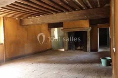 Bâtiment ancien avec façade décrépite, entouré d'une cour herbeuse et d'arbres dénudés en arrière-plan.