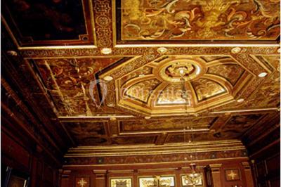 Bâtiment ancien avec façade décrépite, entouré d'une cour herbeuse et d'arbres dénudés en arrière-plan.